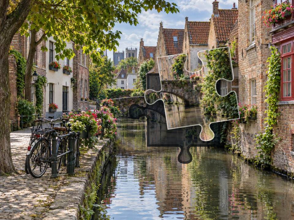 Old brick houses and a small arched bridge reflected in a canal beside a cobbled quay.